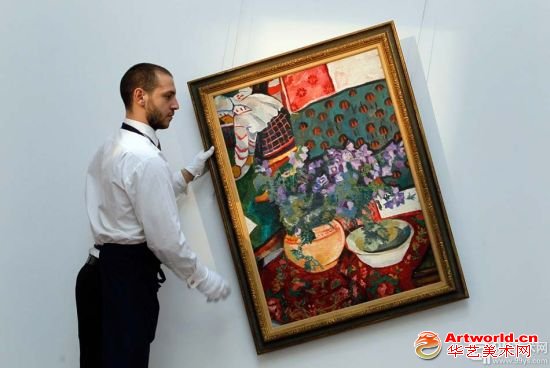 苏富比的一位工作人员正在伦敦苏富比拍卖会悬挂艺术家纳塔利娅·瑟吉维纳·宫察洛娃的绘画作品《静物写生（风铃草）》